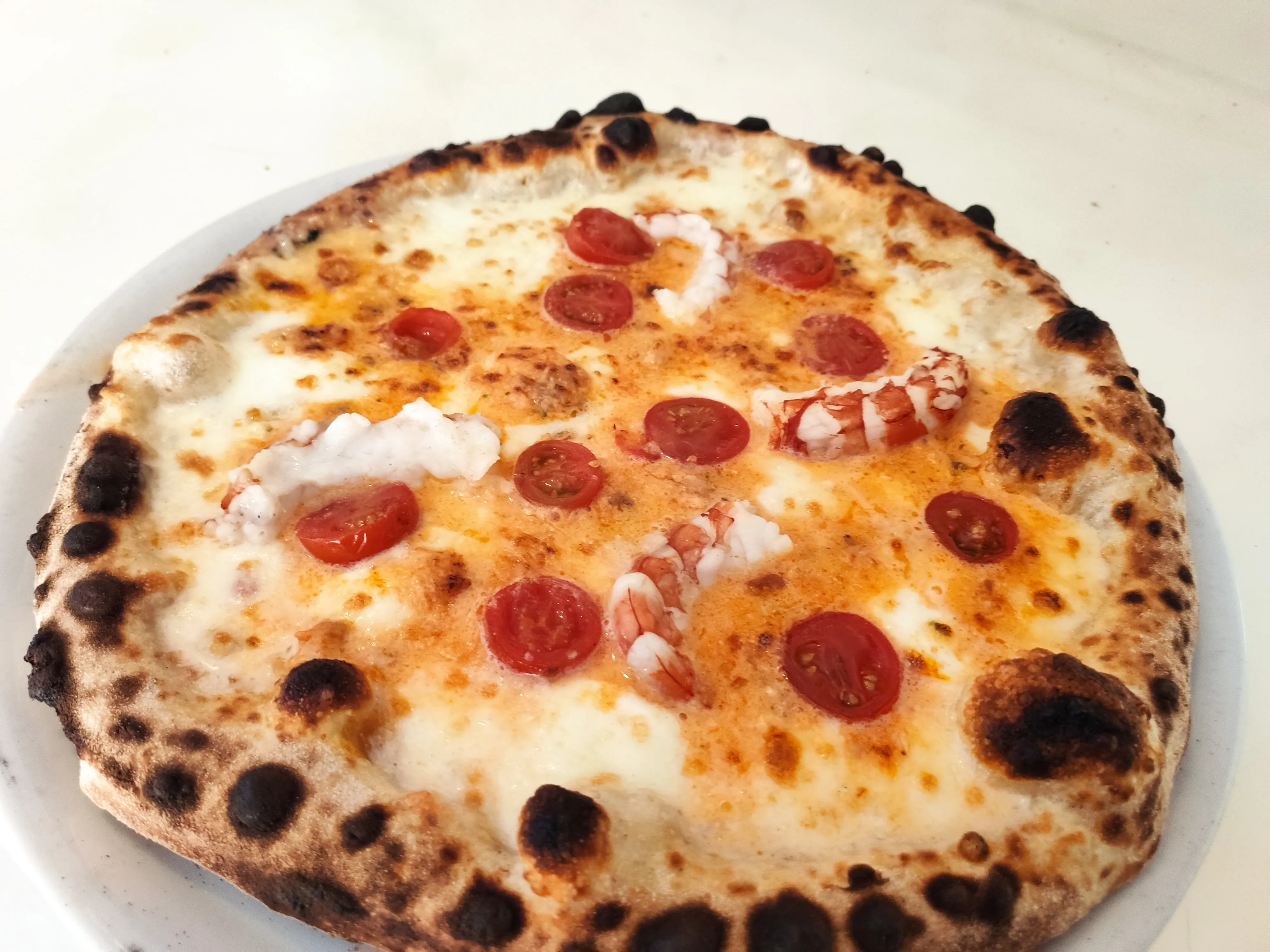 Pizza con pomodorini e gamberi cotta nel forno a legna