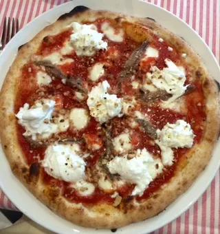 Pizza Napoli DOC - Autentica pizza napoletana preparata secondo la tradizione secolare. Base con pomodoro San Marzano DOP, mozzarella di bufala campana DOP, acciughe del Cantabrico e basilico fresco. Cotta nel forno a legna a 450°C.